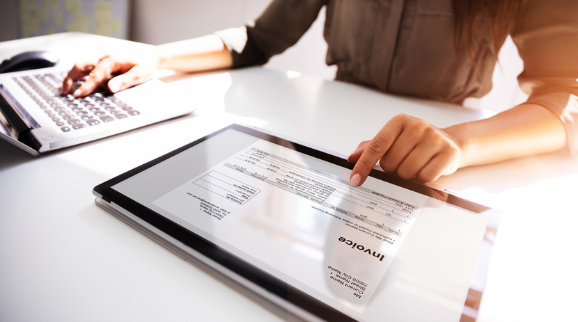 Fonctionnalités - Gros plan de la main d'une femme d'affaires travaillant sur une facture avec une tablette numérique.